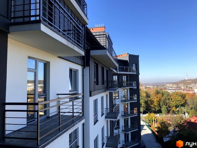 Новобудова на вулиці Черемшини, 29. Фасад будинку з балконами та вікнами, вид на місто та осінні дерева.