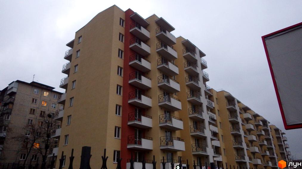 Висотна будівля Житловий комплекс з балконами та вікнами. На передньому плані паркан.