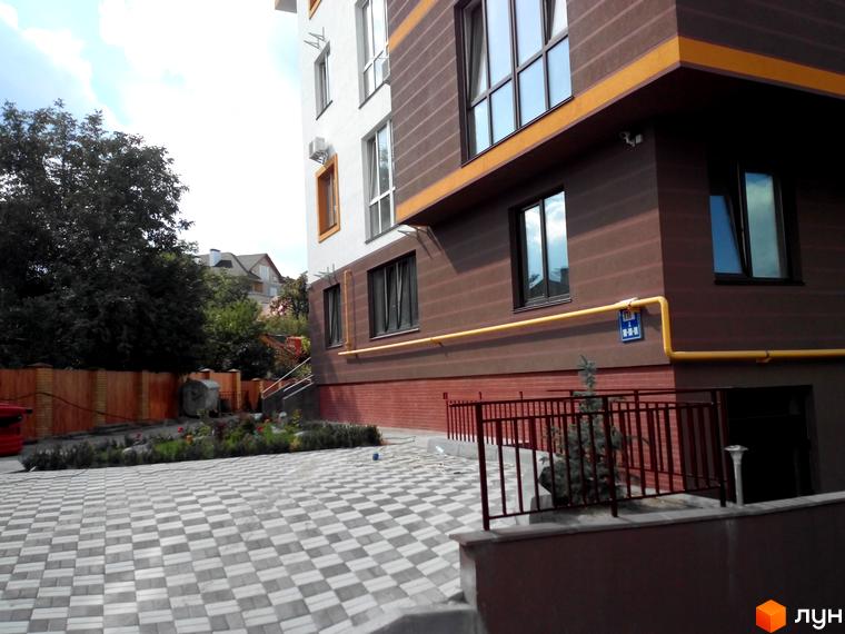 Зовнішній вигляд будівлі Клубний будинок „Чорногорія“. На передньому плані бруківка та невелика прибудинкова територія з рослинами та огорожею.