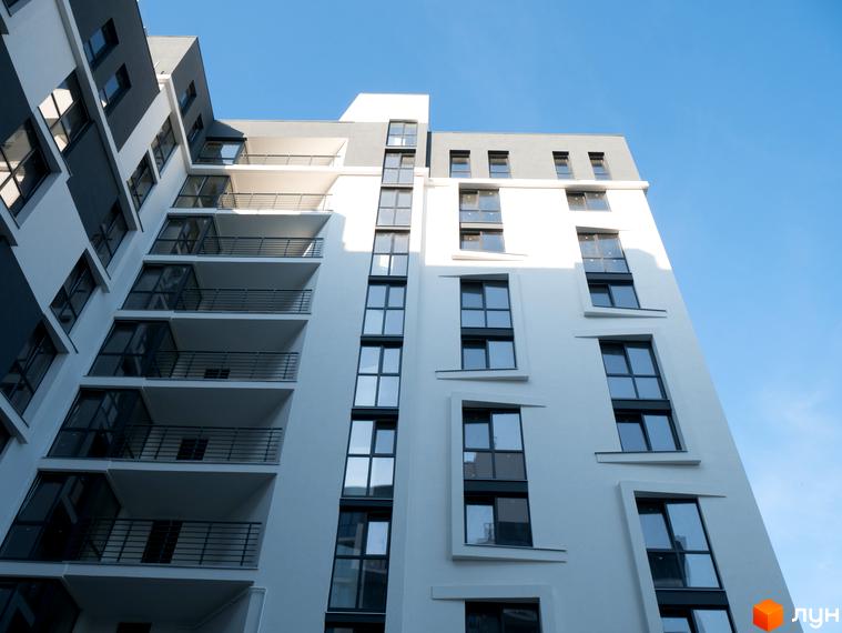 Фасад житлового комплексу 360 з балконами та вікнами на фоні блакитного неба. Сучасна архітектура новобудови.