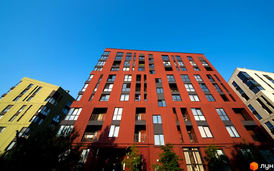 Житловий комплекс Spectrum - це сучасна архітектура з яскравими фасадами та великою кількістю вікон. Комплекс розташований на фоні ясного блакитного неба.