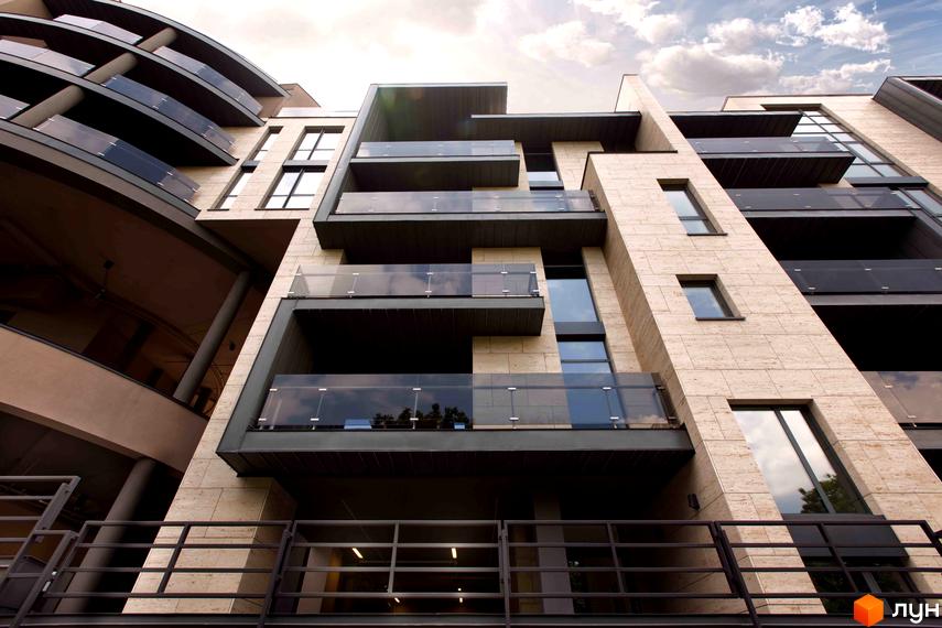 Житловий комплекс Pechersk Hills Residence. Фасад будинку з балконами та скляними огорожами. Вид знизу вгору, сонячна погода.