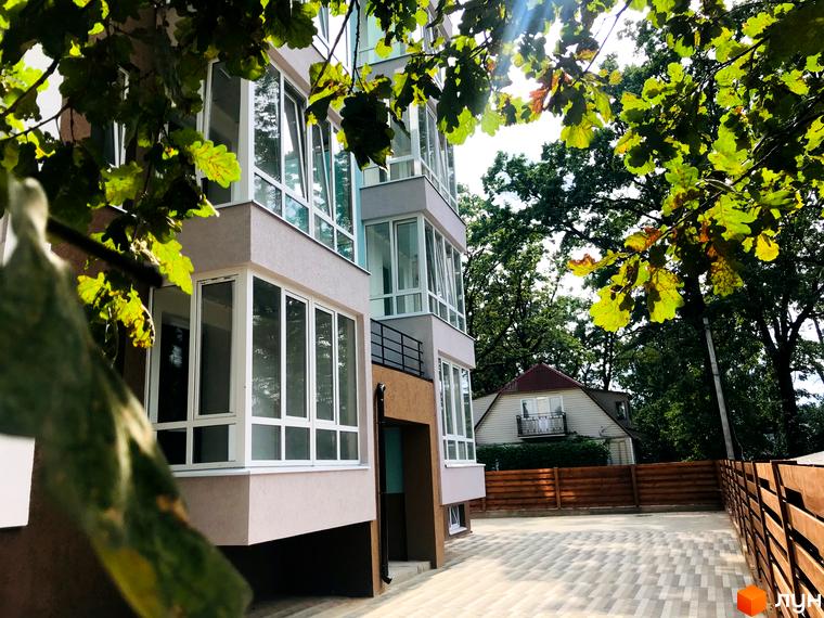 Новобудова ColibriHouse з багатоповерховим фасадом та заскленими балконами. Прибудинкова територія з мощеним покриттям та деревами.