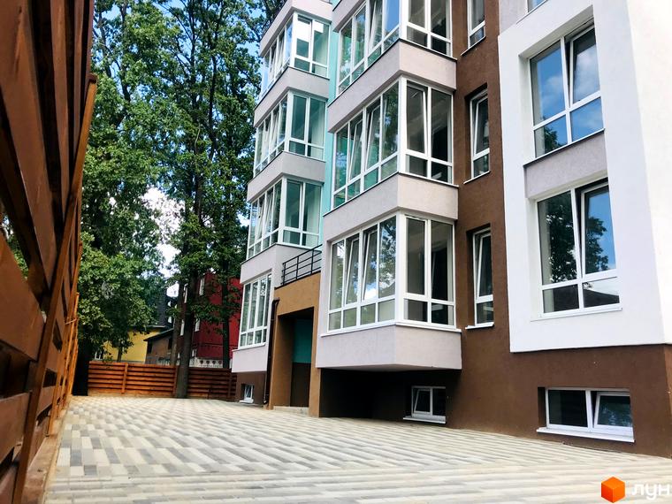 Житловий комплекс ColibriHouse: багатоповерховий будинок з коричневим та світлим фасадом, заскленими балконами. Перед ним вимощений двір та зелені дерева.