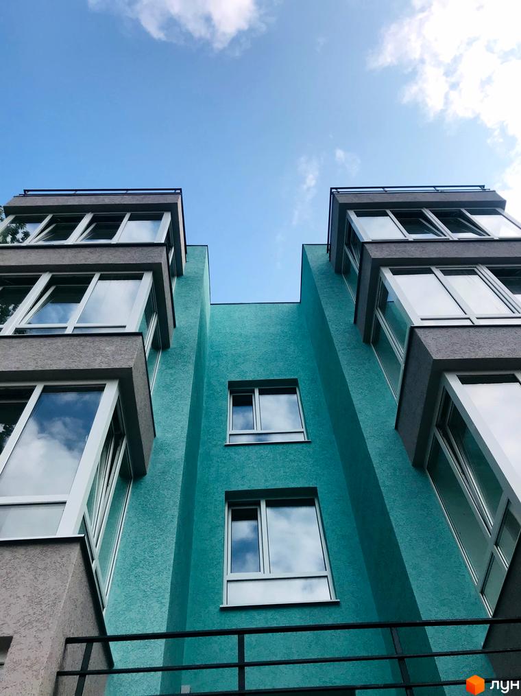 Житловий комплекс ColibriHouse: будівля бірюзового кольору з великими вікнами та сірими елементами, що відбивають небо.