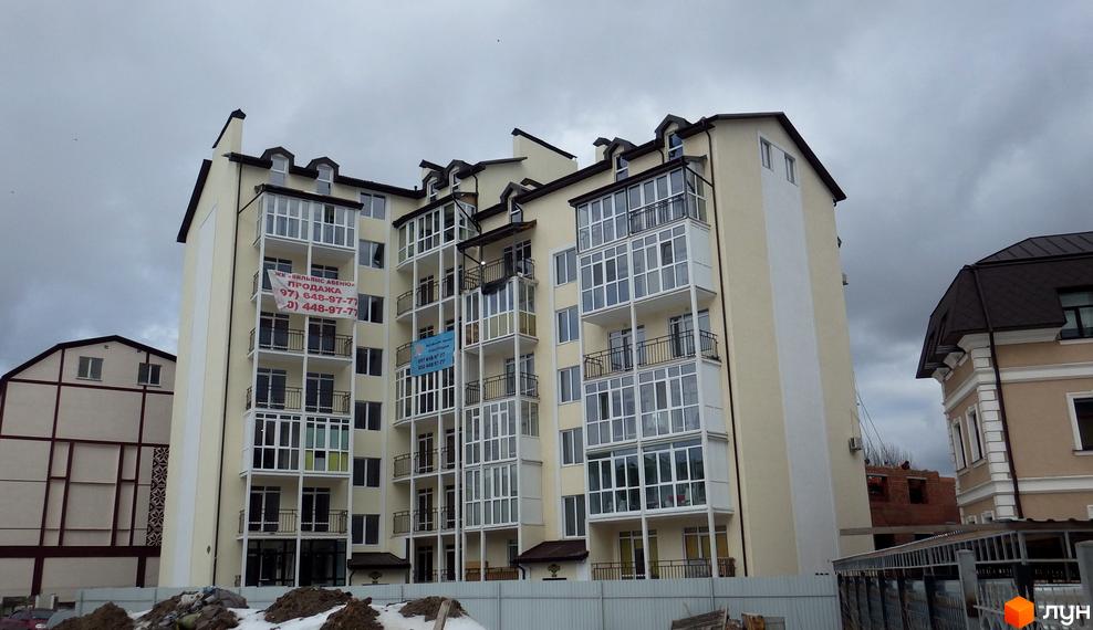 Житловий комплекс Вільямс Авеню з панорамними вікнами. На фасаді будинку розміщено банер з контактною інформацією. Поруч розташовані інші будівлі та паркан.