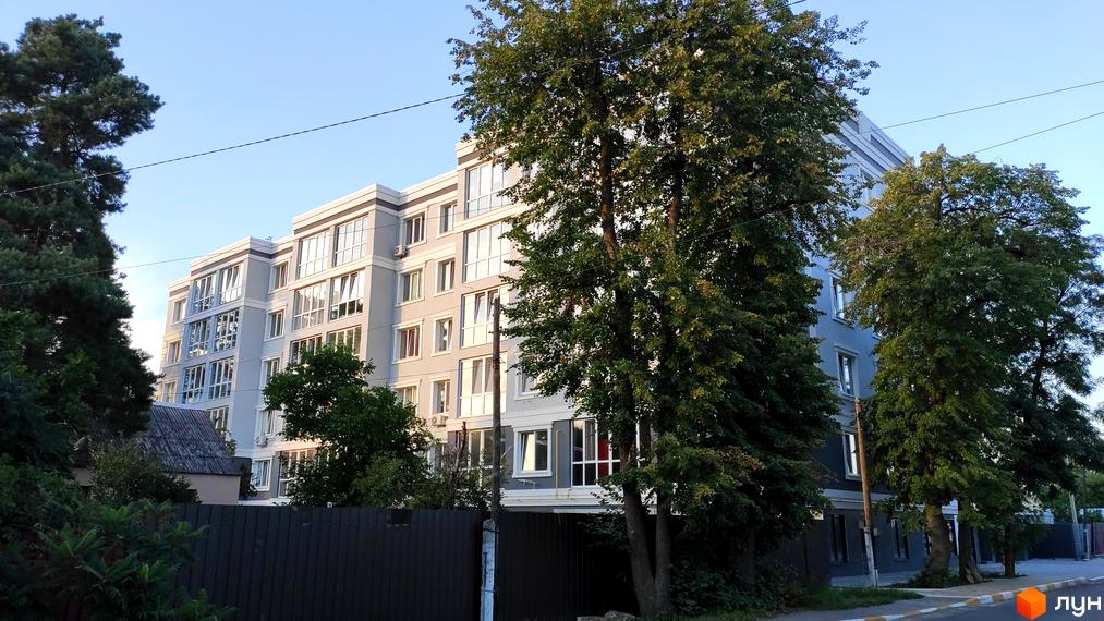 Зовнішній вигляд будинку на вулиці Садова, 6а. Багатоповерхова будівля з великими вікнами, поруч дерева та зелені насадження.