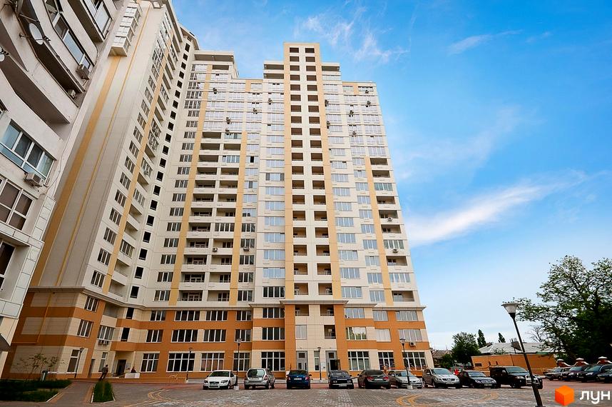 Житловий комплекс Руслан і Людмила з сучасним фасадом та прибудинковою територією, де розташовані автомобілі.