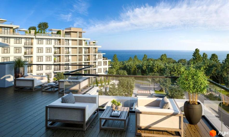 Житловий комплекс MARINIST residence: багатоповерховий будинок з терасами та балконами. На передньому плані облаштована тераса з меблями та видом на море.