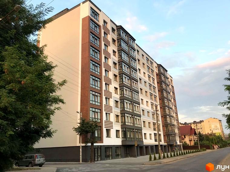 Зовнішній вигляд новобудови на вулиці Берегова 18/1, 18/2, 20 та Чиста, 23. Будинок має багатоповерхову структуру з балконами та вікнами, оточений деревами та вулицею.