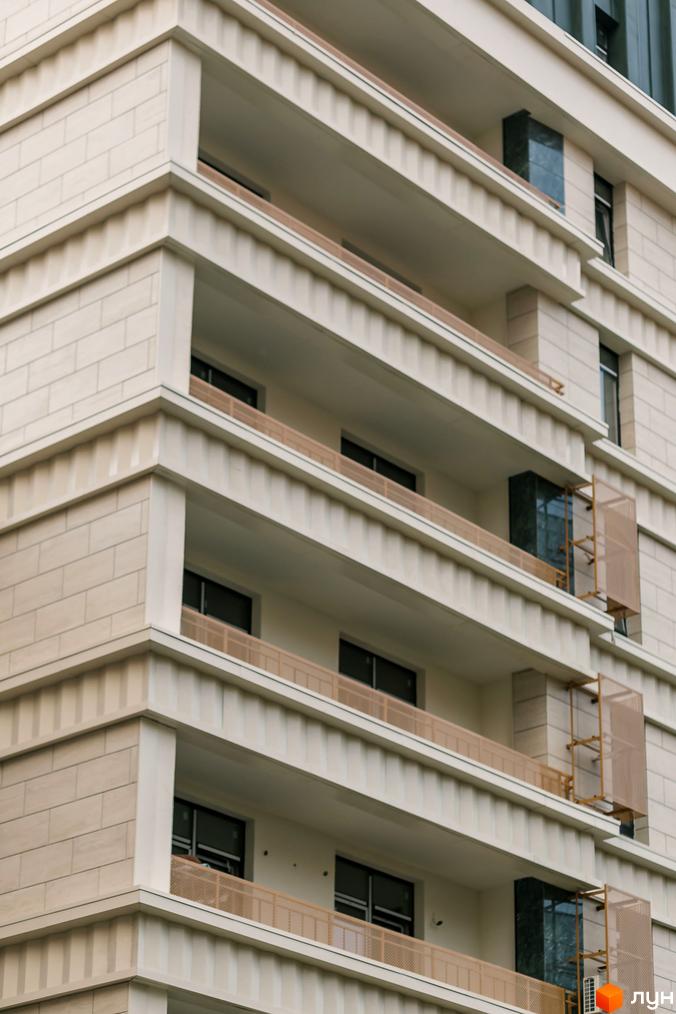 Житловий комплекс Einstein Concept House: фасад багатоквартирного будинку зі світлої плитки, балкони з бежевими огорожами та темними вікнами.