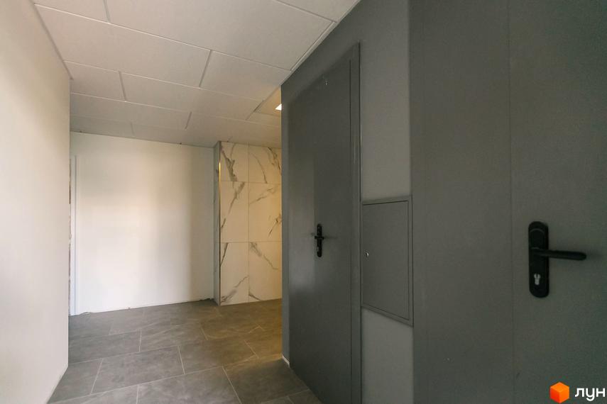 Інтер'єр холу Житлового комплексу Einstein Concept House: сіра плитка на підлозі, білі стіни, сірі двері та стіна з мармуровою плиткою.