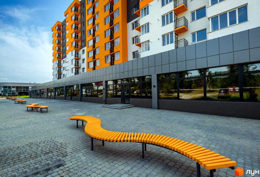 Житловий комплекс Сімейний COMFORT з яскравим фасадом та прибудинковою територією з оригінальними лавками. Зовнішній вигляд новобудови та її благоустрій.