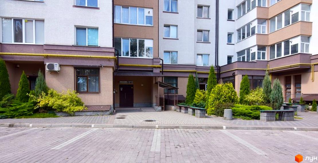 Зовнішній вигляд будинку на Целевича, 4а. На передньому плані прибудинкова територія з ландшафтним дизайном та парковкою.