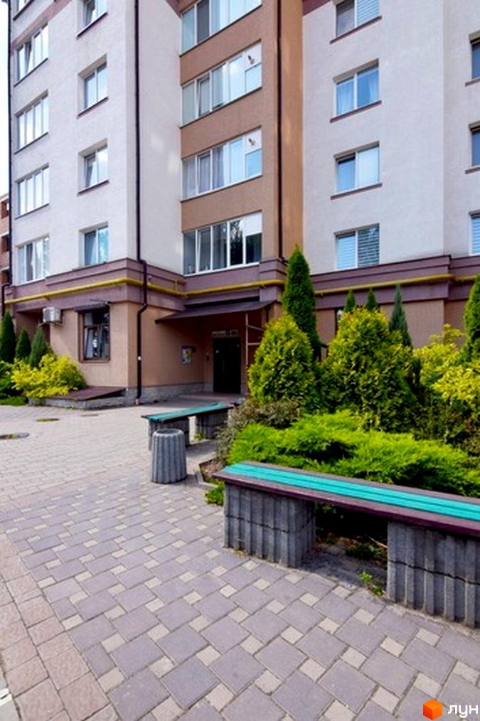 Зовнішній вигляд житлового будинку на вул. Целевича, 4а. На передньому плані – прибудинкова територія з лавками та зеленими насадженнями.