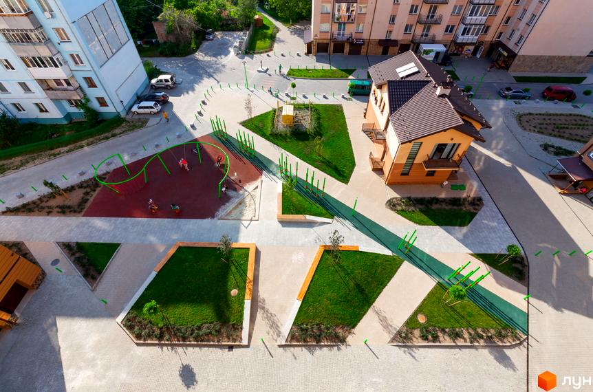 Житловий комплекс Нова оселя плюс: вид зверху на сучасний житловий будинок та зелену прибудинкову територію з дитячим майданчиком та зонами відпочинку.