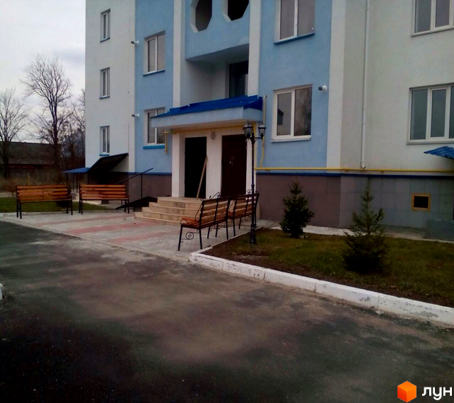 Зовнішній вигляд новобудови на вул. Грушевського, 108а, з прибудинковою територією та лавками.