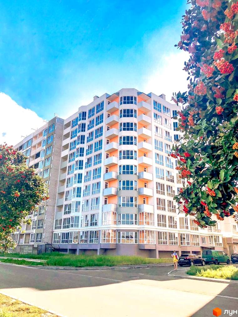Зовнішній вигляд житлового комплексу на вулиці Жабинського, 2д, 2в, 2е з численними балконами та великими вікнами. Навколо комплексу зелена зона та дорога з припаркованими автомобілями.