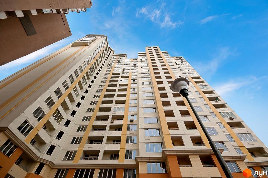 Житловий комплекс Руслан і Людмила з висоти, з фасадом та балконами. Прибудинкова територія з ліхтарем на фоні ясного неба.