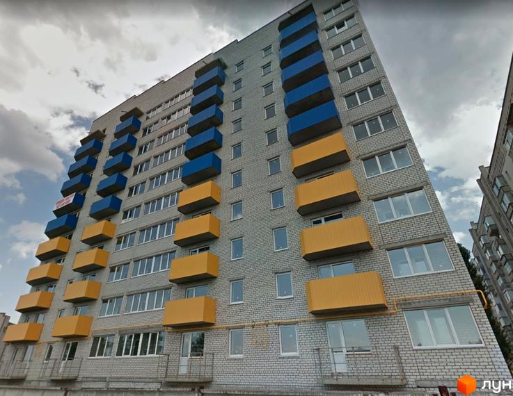 Зовнішній вигляд багатоповерхового будинку з жовтими та синіми балконами на вулиці Конституції, 48. Навколо будинку видно хмарне небо.