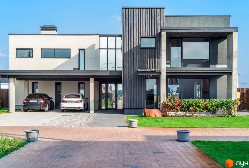 Котеджне містечко На Щасливій: сучасний двоповерховий будинок з панорамними вікнами та навісом для двох автомобілів. Прибудинкова територія з газоном та бруківкою.