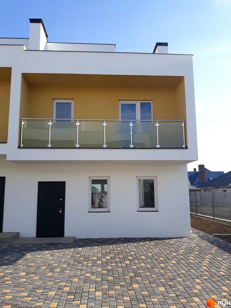 Фасад будинку Domino Townhouse з балконом та вікнами, вимощений двір з бруківки.