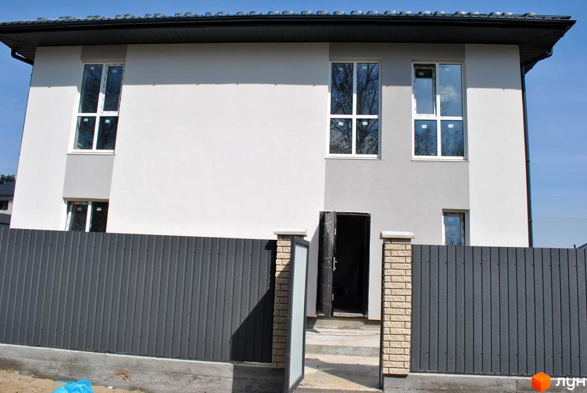 Будинок з сірим та білим фасадом, великими вікнами та металевим парканом. Навколо будинку облаштована прибудинкова територія.