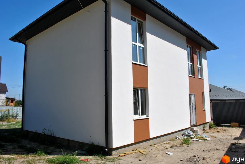 Новобудова на вул. Івана Франка, 34-36 з біло-коричневим фасадом та вікнами. На прибудинковій території видно будматеріали та зелень.