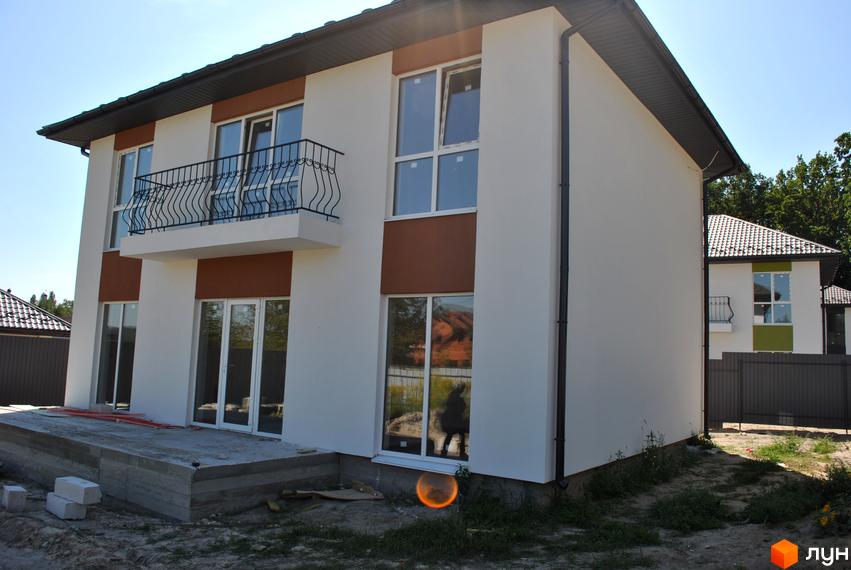 Зовнішній вигляд двоповерхового будинку з балконом та великими вікнами на вулиці Івана Франка, 34-36. Територія навколо будинку частково облаштована.