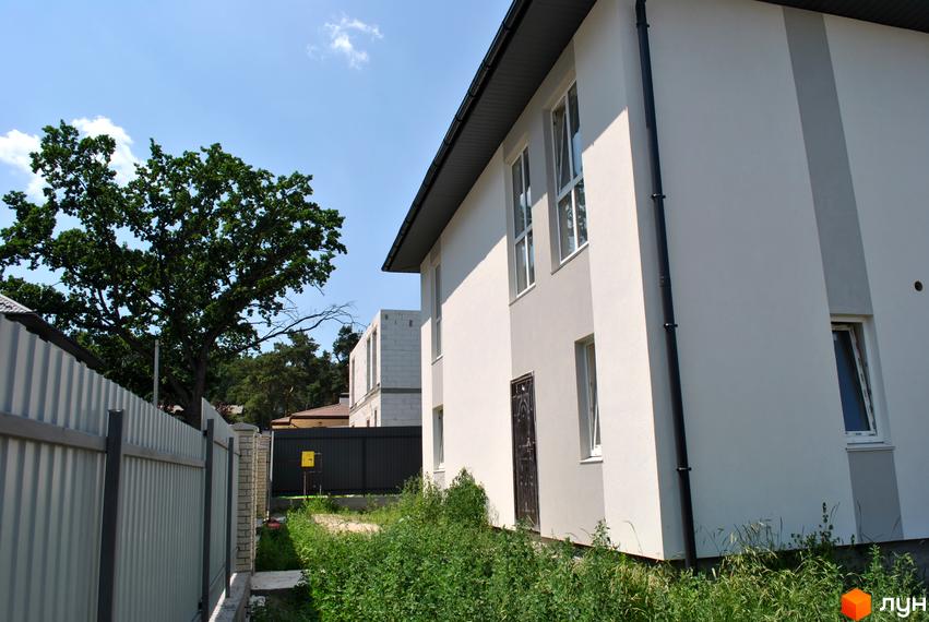 Будинок з білою штукатуркою та темним дахом на вулиці Івана Франка, 34-36. Навколо будинку зелена трава та паркан.