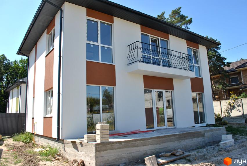 Фасад новобудови на вул. Івана Франка, 34-36 з біло-коричневими елементами та балконом. Навколо будівельний майданчик з матеріалами.