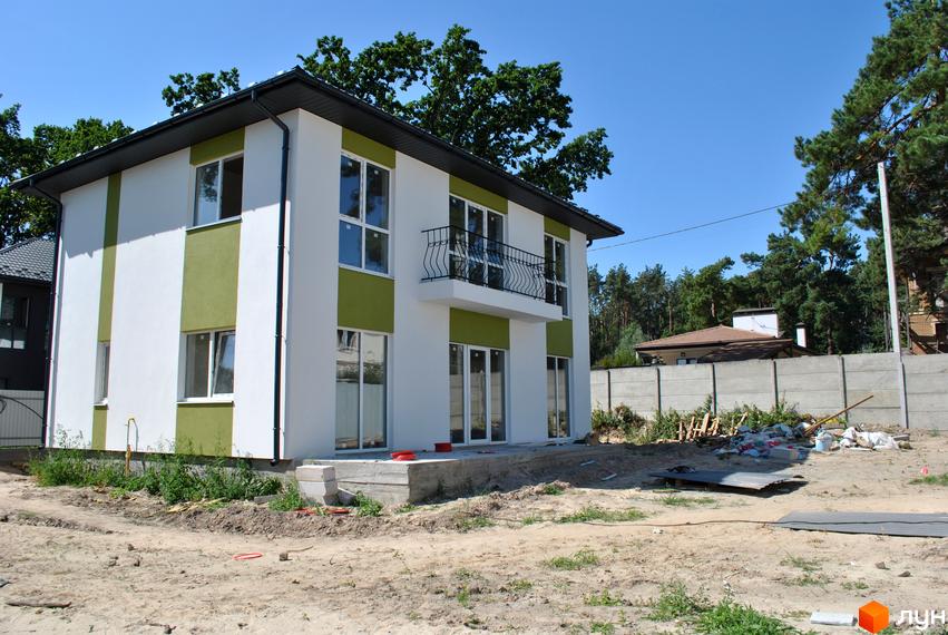 Сучасний двоповерховий будинок з біло-зеленим фасадом та балконом на вулиці Івана Франка, 34-36. Прибудинкова територія з будівельними матеріалами.