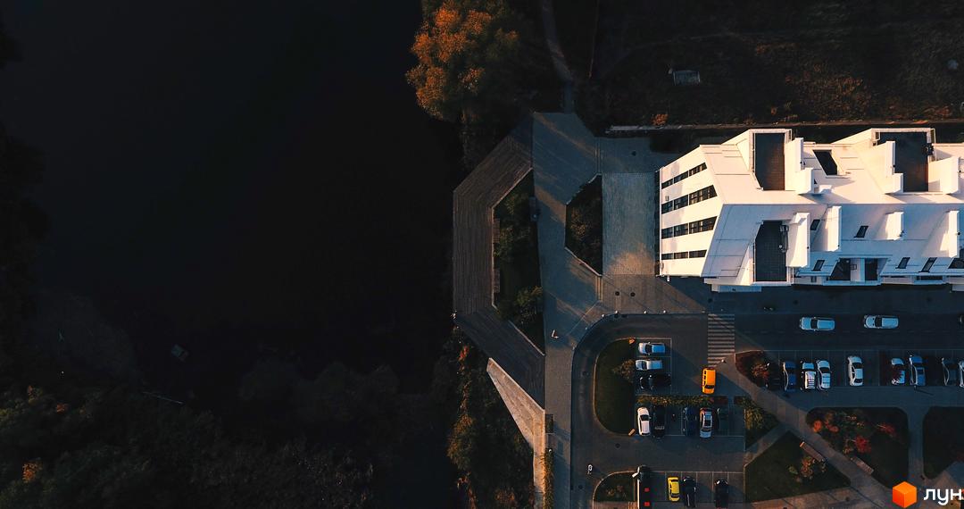 Житловий комплекс City Lake: білий багатоповерховий будинок з багатоскатним дахом, паркінг та водойма поруч.