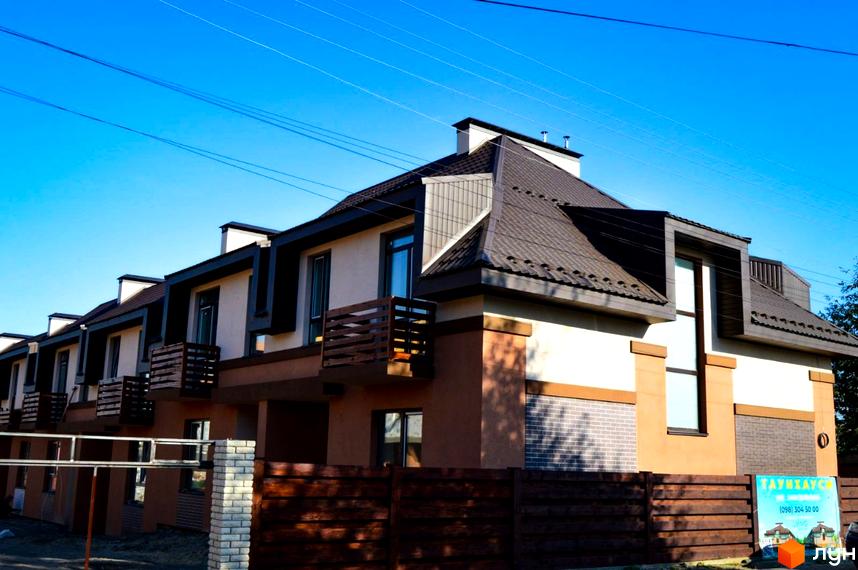 Зображення таунхаусів Житлового комплексу „Озерний“ з коричневим дахом та балконами. Вид на фасад будинку та прибудинкову територію.