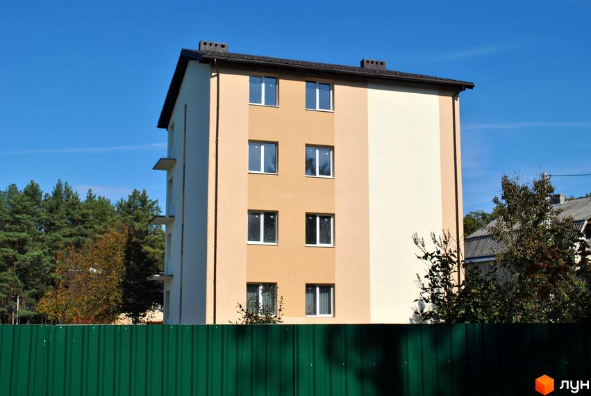 Будинок житлового комплексу на вулиці Спортова, 12, з фасадом у двох кольорах та вікнами. Навколо будинку дерева та зелений паркан.