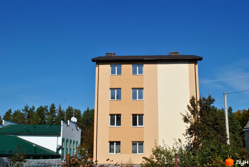 Будівельний проєкт на вул. Спортова, 12. Фасад будинку оздоблений світлими відтінками бежевого та кремового кольорів. Навколо будівлі видно зелені дерева та сусідні споруди.