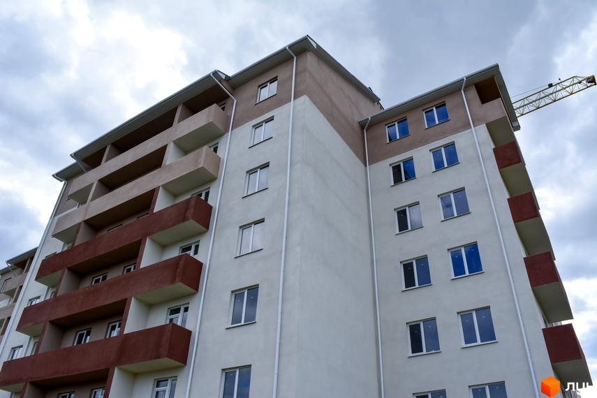 Багатоповерховий житловий будинок Житловий комплекс Авангард з бежевим фасадом та коричневими балконами. На задньому плані видно будівельний кран.