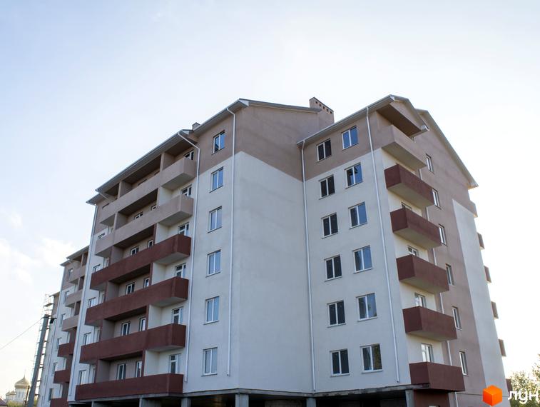 Зображення фасаду та балконів Житлового комплексу Авангард. Багатоповерховий будинок з великими вікнами та коричневими балконами.