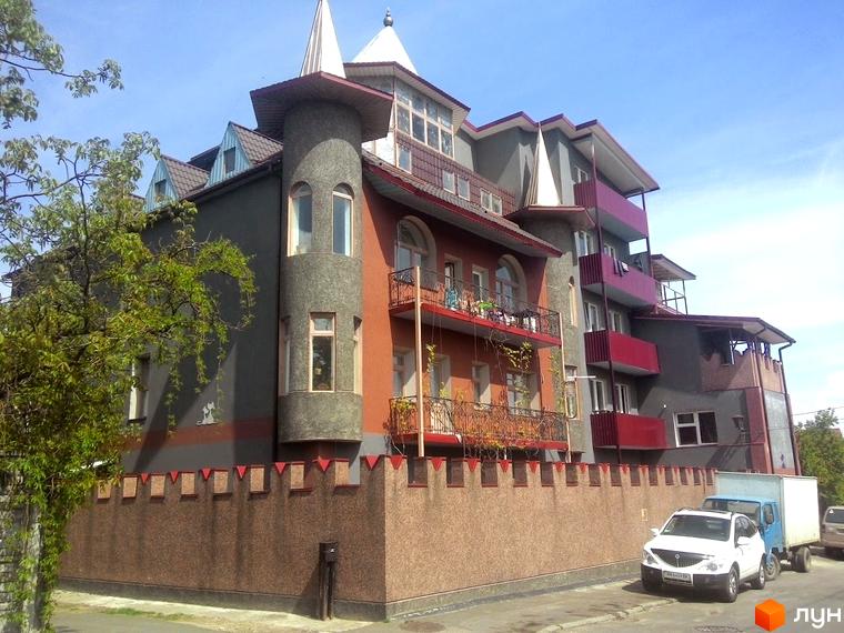 Житловий комплекс Фортеця з унікальною архітектурою та фортечною стіною. Зовнішній вигляд новобудови з балконами та вежею.