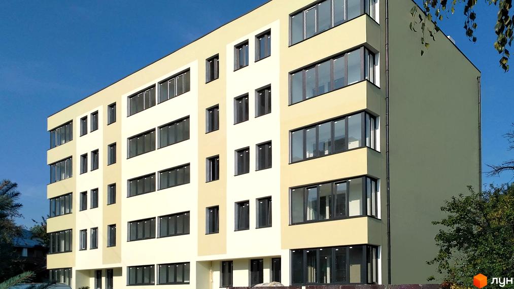 Новобудова на вулиці Уляни Кравченко, 13. Будинок має світло-жовтий фасад з великою кількістю вікон та балконів, оточений деревами.