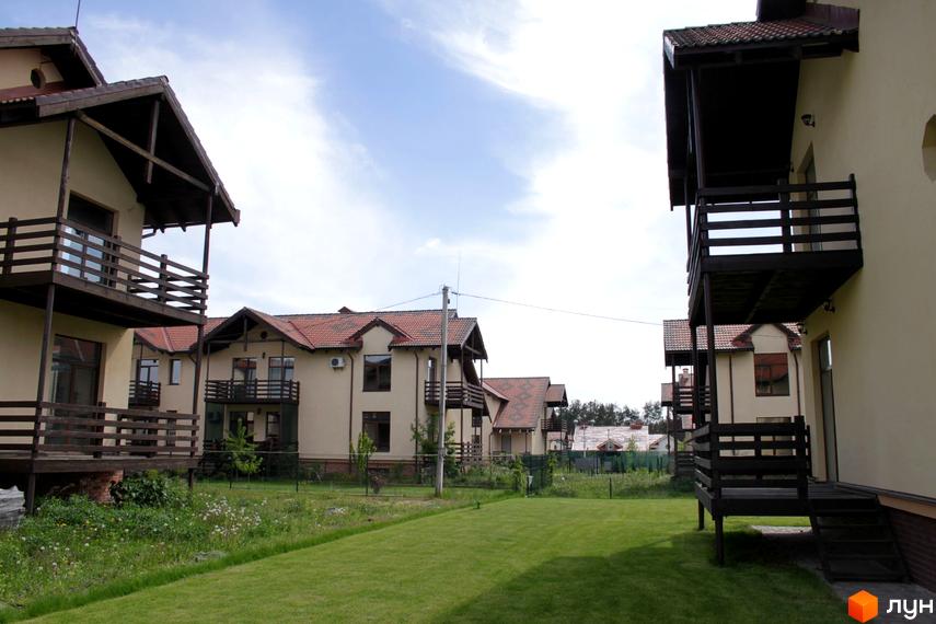 Зображення житлових будинків у Котеджному містечку Садок Вишневий. Будинки з балконами та терасами, вкриті черепицею. На території доглянутий газон.