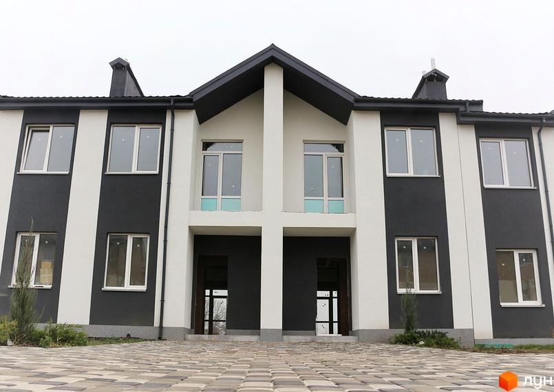 Фасад новобудови на вул. Грушевського, 30, 32, з білими та сірими смугами, великими вікнами та вимощеною бруківкою прибудинковою територією.