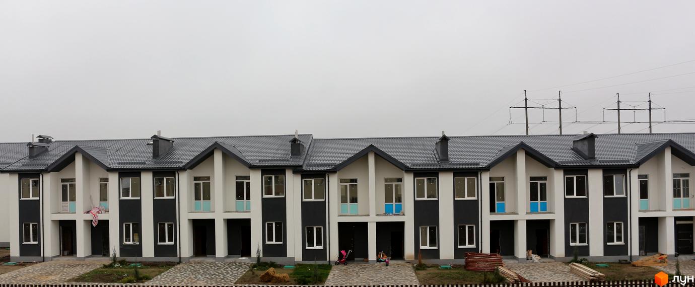 Новобудова на вул. Грушевського, 30, 32. Фасад будинку біло-темно-сірий, дах темно-сірий. Поруч облаштована прибудинкова територія з доріжками.