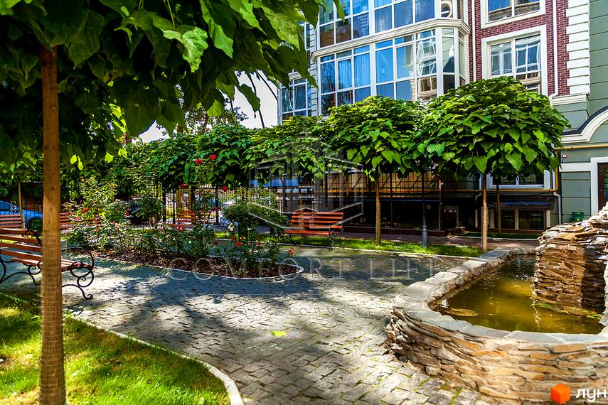 Житловий комплекс Британіка: фасади будівель з панорамними вікнами та зелена прибудинкова територія з ландшафтним дизайном, фонтаном та зонами відпочинку.