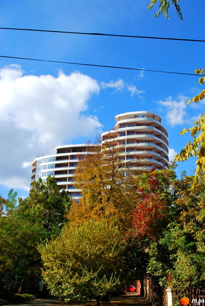 Житловий комплекс Ланжерон з сучасною архітектурою на фоні зелених дерев і блакитного неба.