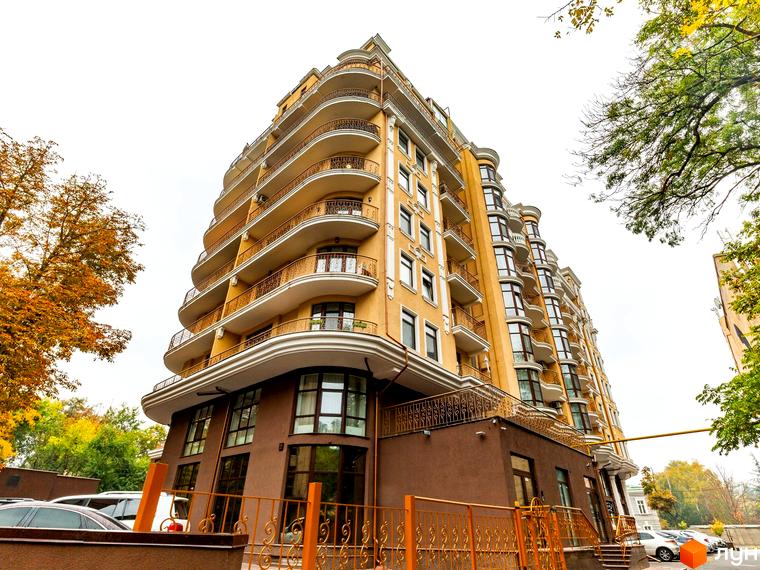 Житловий комплекс ЖК Крит з фасадом жовтого кольору та балконами, оточений зеленими деревами та прибудинковою територією.