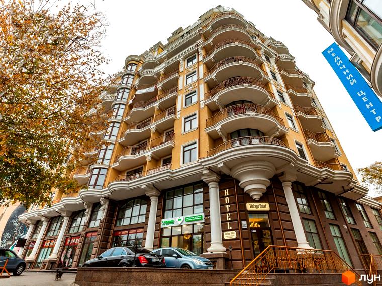 Житловий комплекс ЖК Крит з фасадом жовтого кольору та балконами. Прибудинкова територія з автомобілями та зеленими насадженнями.