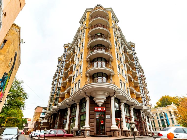 Житловий комплекс ЖК Крит з фасадом з балконами та вхідною групою. Прибудинкова територія з автомобілями та зеленими насадженнями.