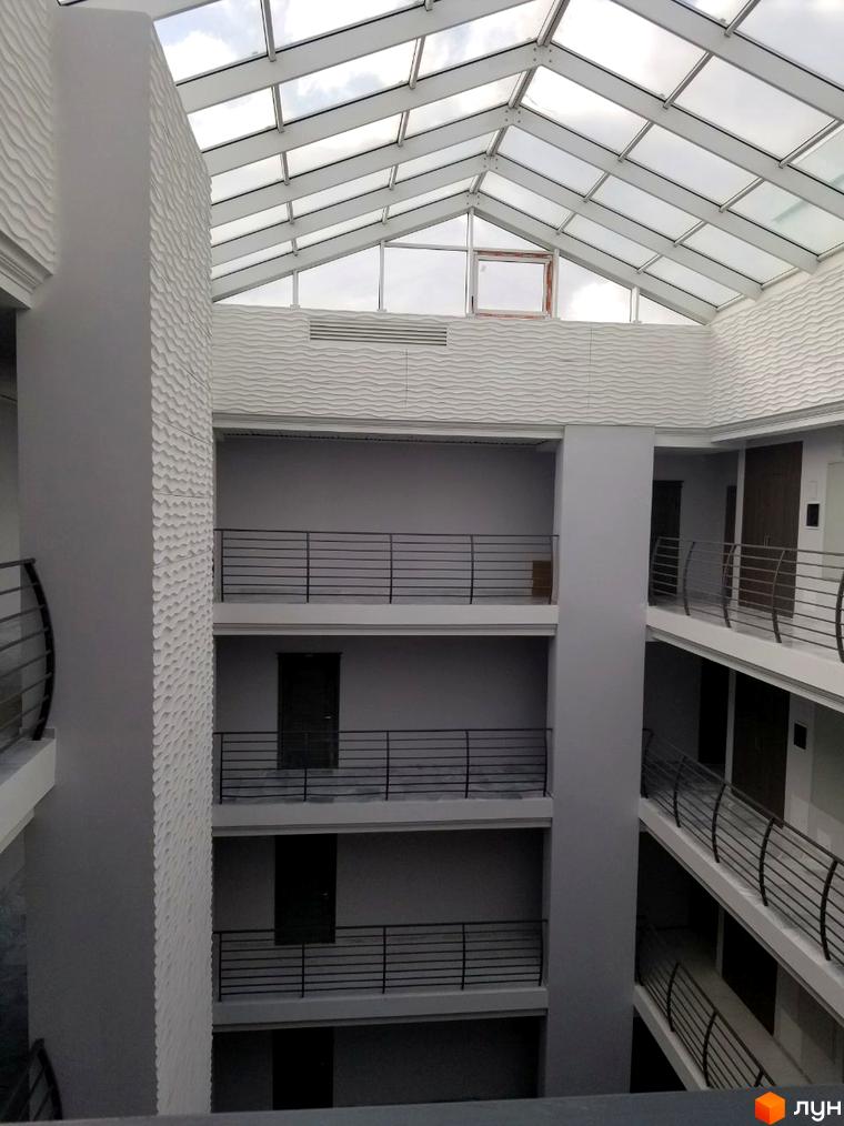 Житловий комплекс Santorini. Архітектура будинку з скляним дахом та балконами. Всередині будівлі просторо та світло.