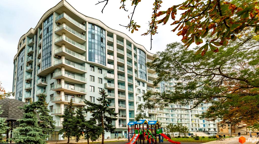 Житловий комплекс Santorini з балконами та панорамними вікнами. На території розташований дитячий майданчик та зелені насадження.